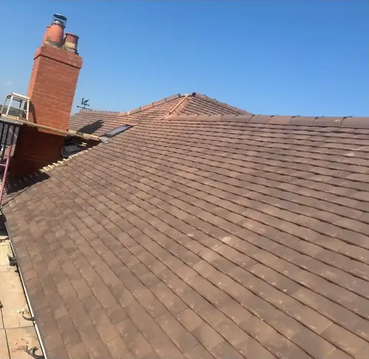 Clay tile pitched roof running up to a brick chimney stack