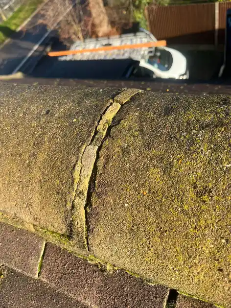 Cracked mortar joint between moss-covered ridge tiles