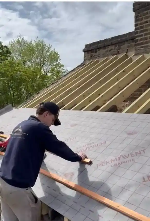 Roofer fixing a batten over breathable membrane