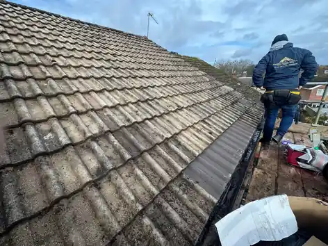 Roofer stripping the old concrete tiles off a pitched roof
