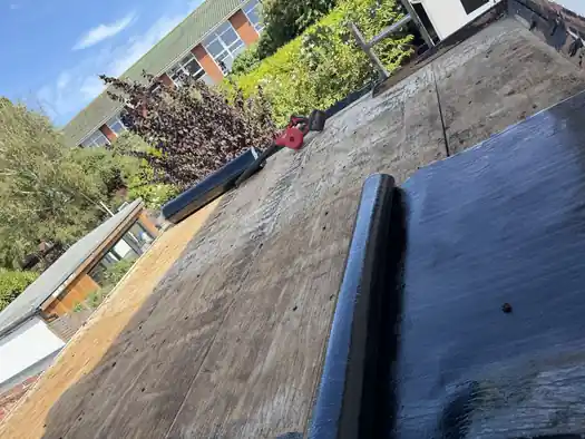 Roll of torch-on felt being laid onto a new plywood flat roof deck