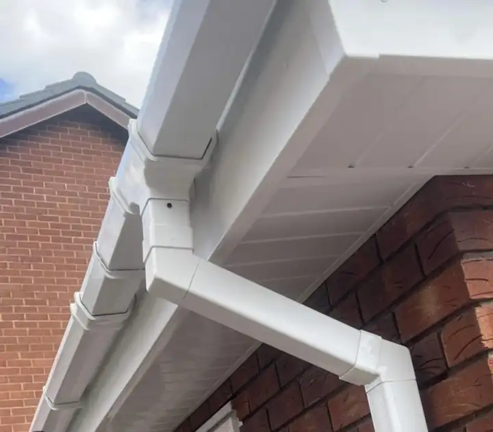 New white uPVC soffit, box end and gutter running round the corner of a brick house